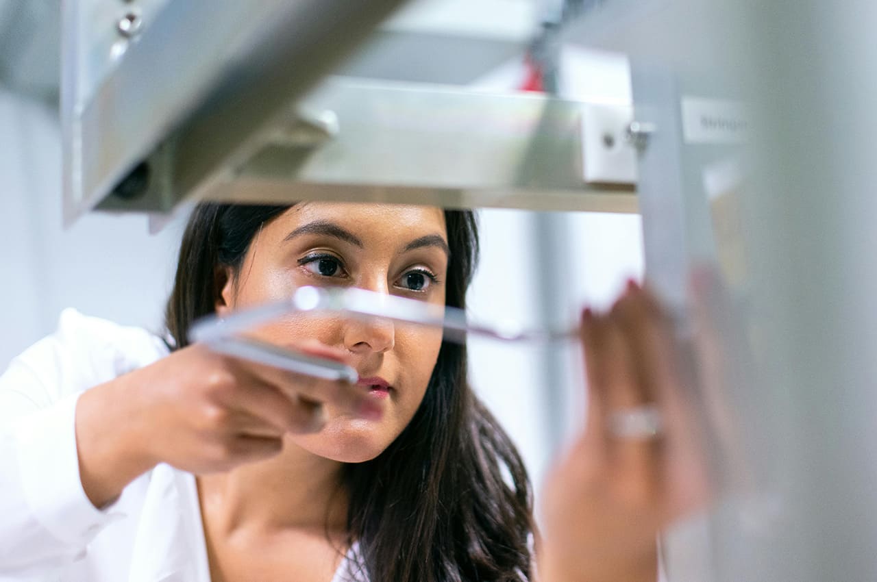 Mujer investigadora en laboratorio, inspeccionando maquinaria de alta tecnología, símbolo de la innovación y calidad industrial española."